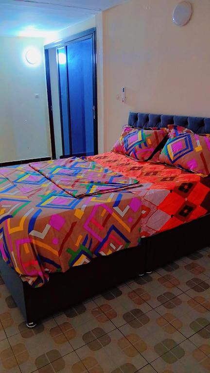 a bed with a colorful comforter in a bedroom at Vivo immobilier in Diakhaté