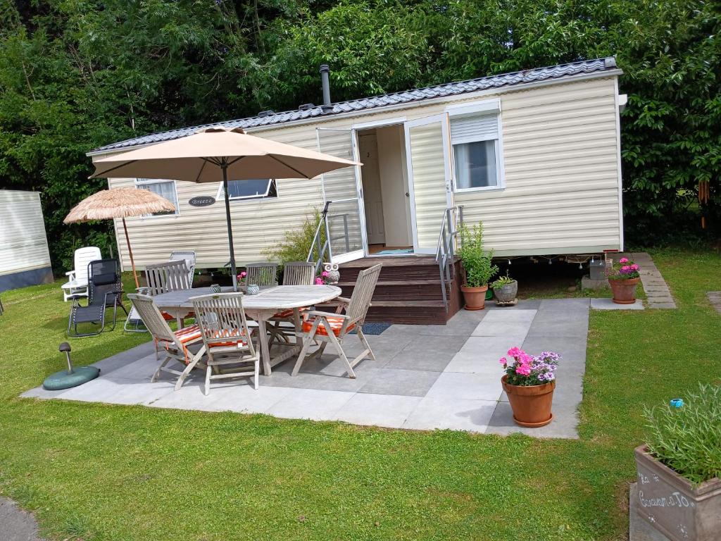 a patio with a table and chairs and an umbrella at La caravan-à-JO in Aywaille