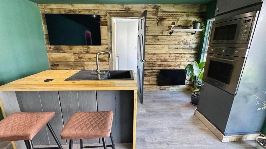 a kitchen with a sink and a counter with stools at Self contained cabin - The VenU in Bristol
