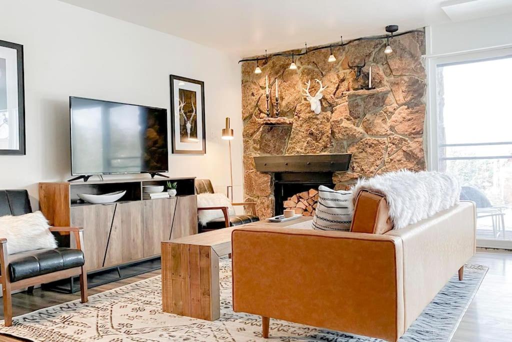 a living room with a stone fireplace and a tv at Modern Mountainside Chalet in Steamboat Springs