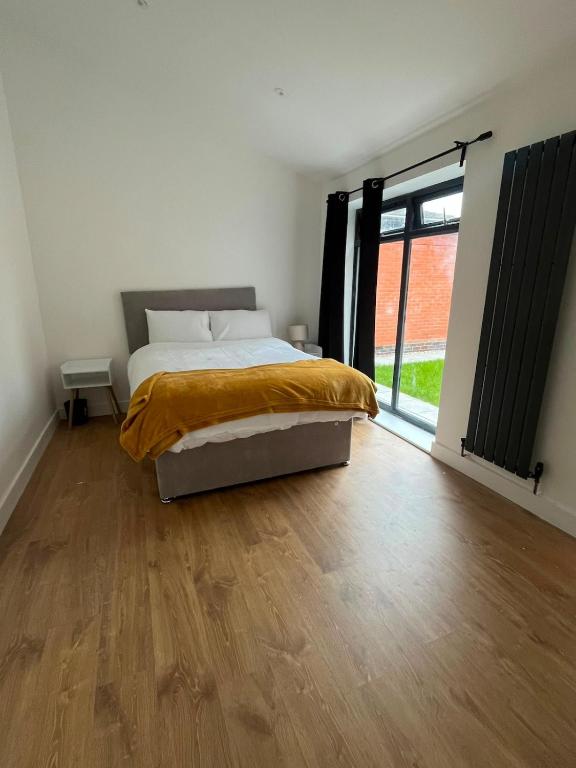 a bedroom with a bed and a wooden floor at Beeston Bungalow in Nottingham