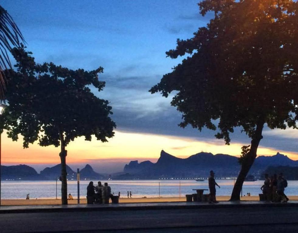 a group of people standing on a beach at sunset at Dream Home Icaraí Niterói in Niterói
