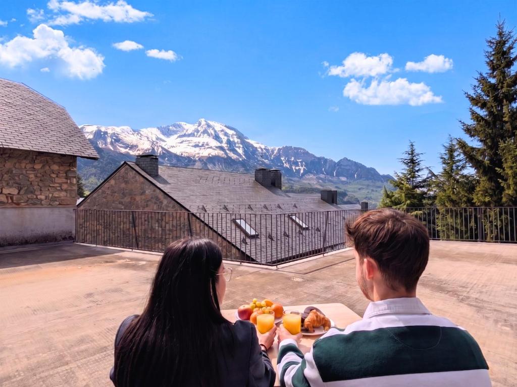 a man and a woman sitting at a table with food at Apartamento Casa Blanca in Tramacastilla de Tena