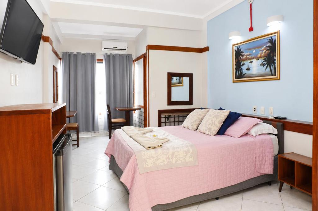 a bedroom with a bed and a flat screen tv at Hotel São Charbel in Ubatuba