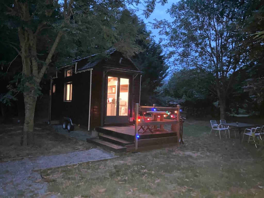 a tiny house with a porch and a table at Tiny House Insolite avec Escape Game in Chanzeaux