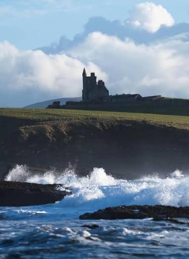 a castle sitting on top of a hill next to the ocean at Slievebawn Accommodation in Sligo