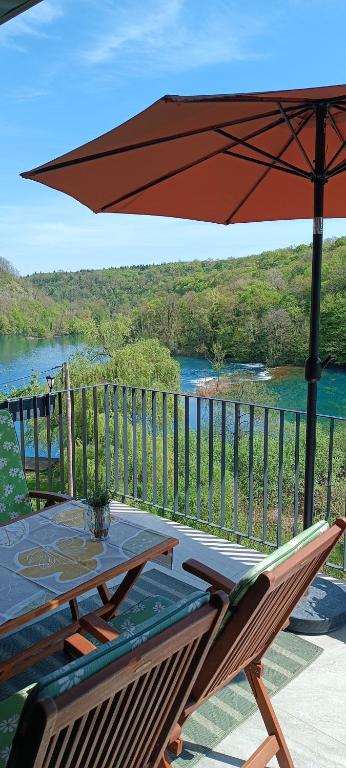 a patio table with an umbrella and a view of a river at Rivera House Mrežnica in Generalski Stol