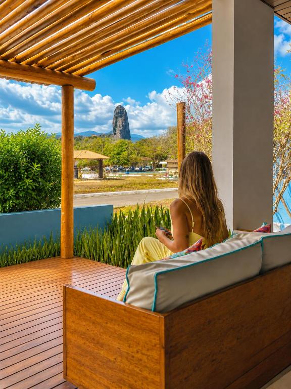 a woman sitting on a deck looking out at the view at Pousada Alto da Vila Noronha by Alto da Ilha in Fernando de Noronha