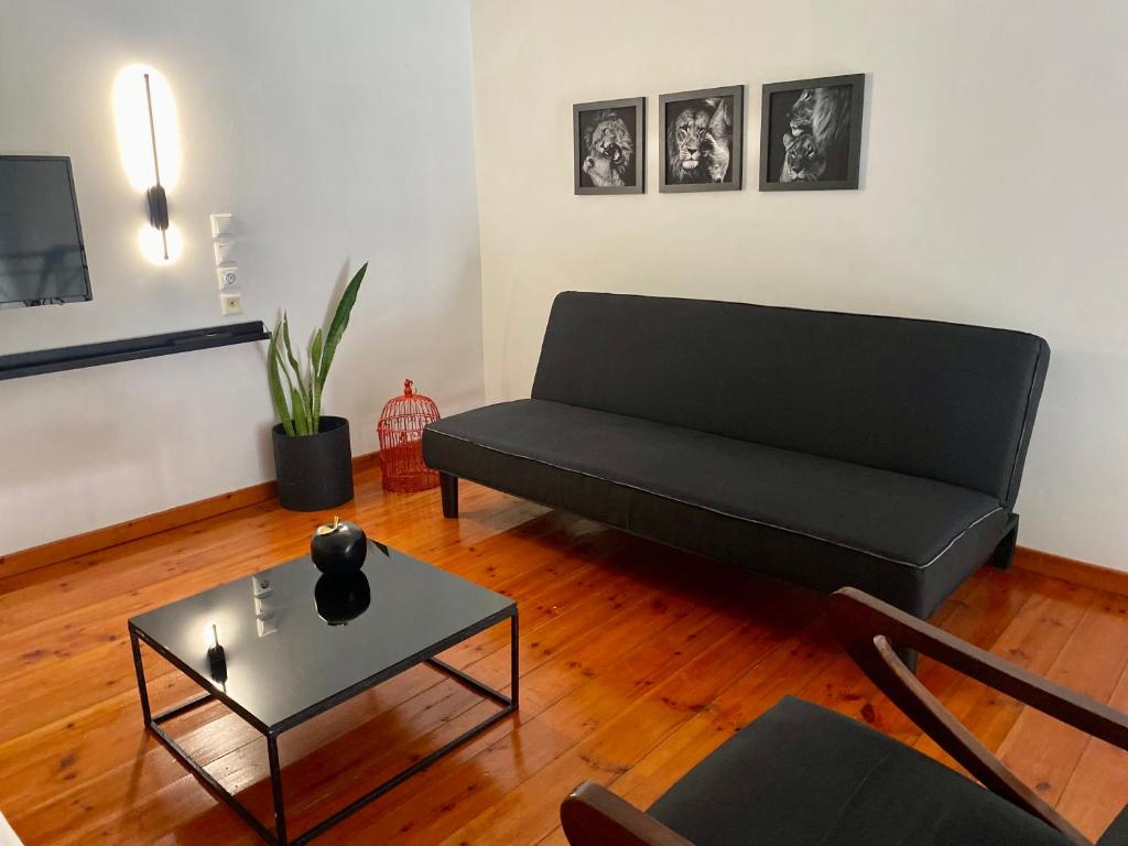 a living room with a black couch and a table at A&D Houses No3 in Patra