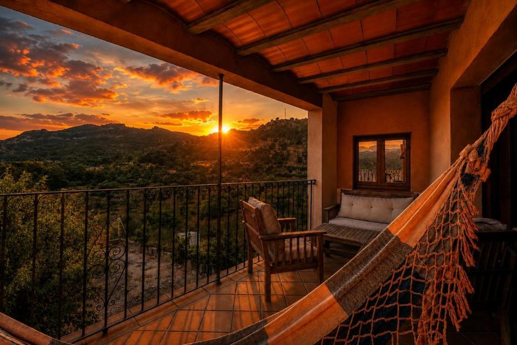 a hammock on a balcony with a sunset at Casa rural en Terra Alta con vistas al Tossal d'Engrilló, cerca de la Vía Verde, espacios exteriores, doble barbacoa, ideal para familias, grupos y mascotas in Prat de Compte