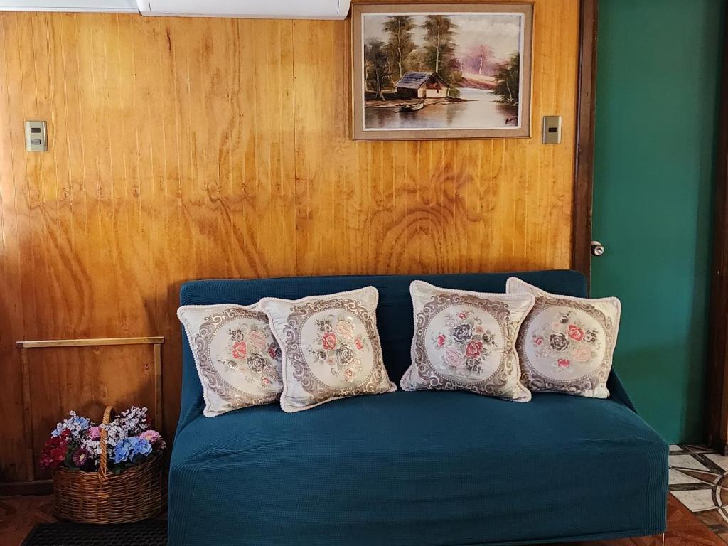 a blue couch with four pillows on it in a room at Cabaña La Petita in Cherquenco