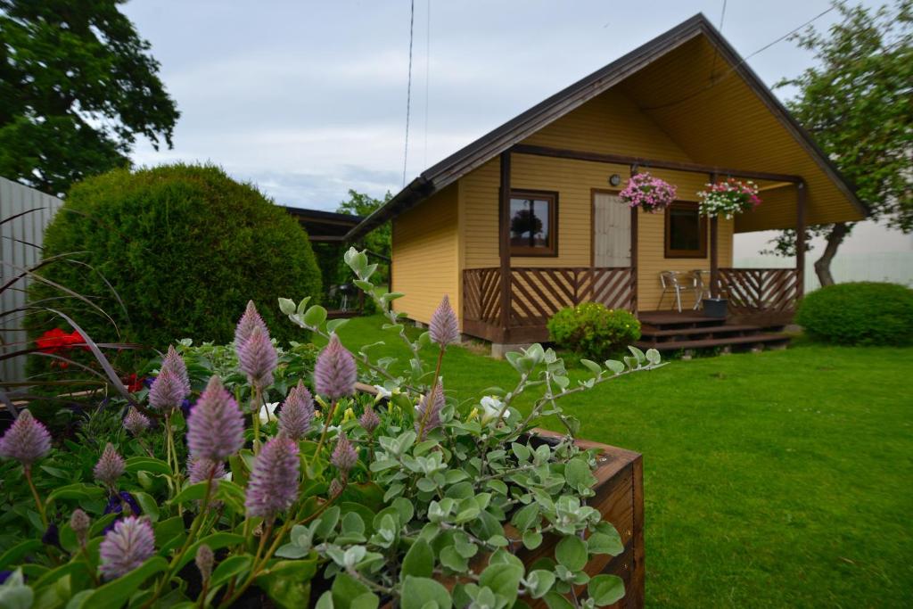 a small yellow house with flowers in the yard at Jaani Puhkemaja in Pärnu