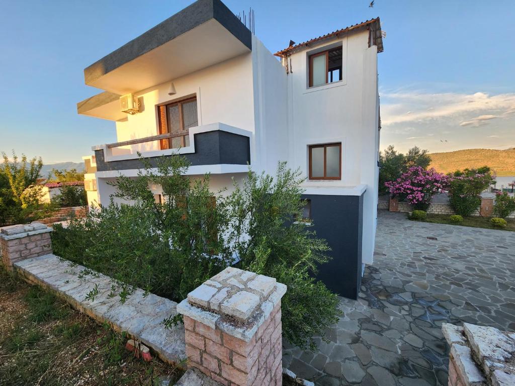 a white house with a stone driveway in front of it at Mihal Suites in Sarandë