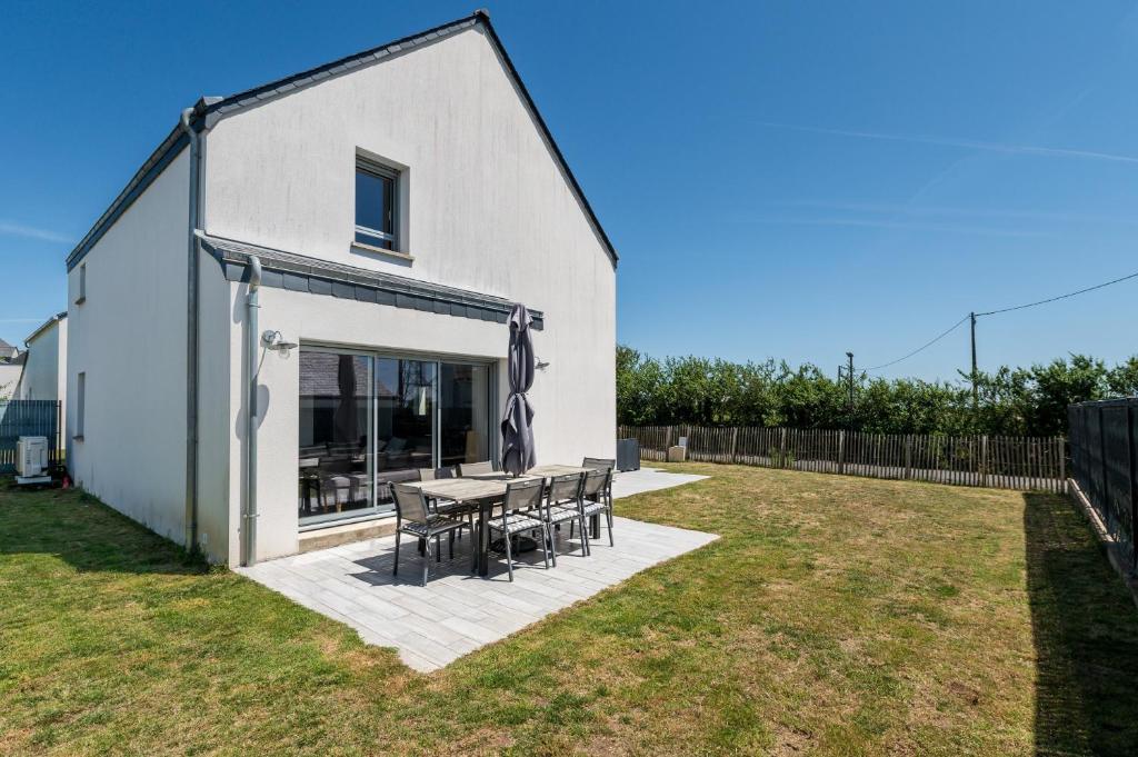 a house with a table and chairs in a yard at Maison de vacances Plouharnel 3star in Plouharnel