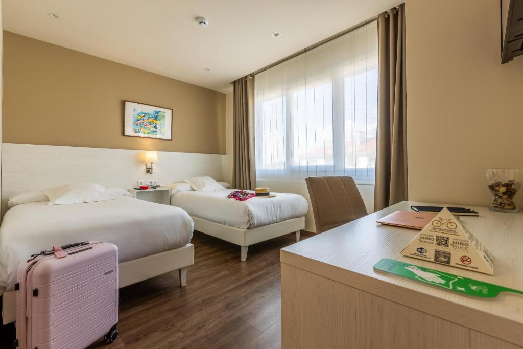 a hotel room with two beds and a desk at Hotel La Terraza in Miño