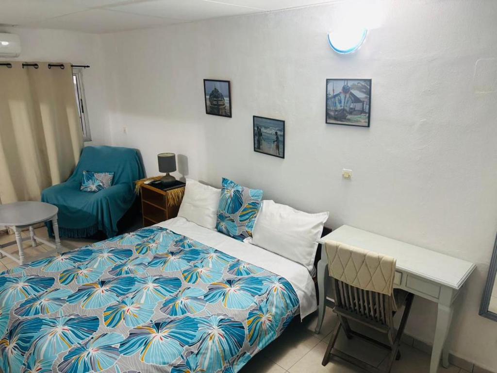 a bedroom with a bed and a table and a chair at Chambres d'hôtes WAIMEA in Abidjan