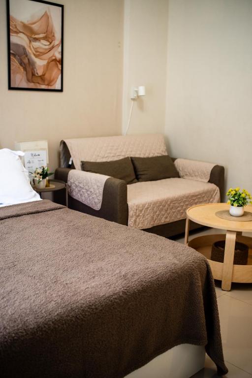 a bedroom with a bed and a couch and a table at Crosswinds Tagaytay Holiday Home by KTCH in Tagaytay
