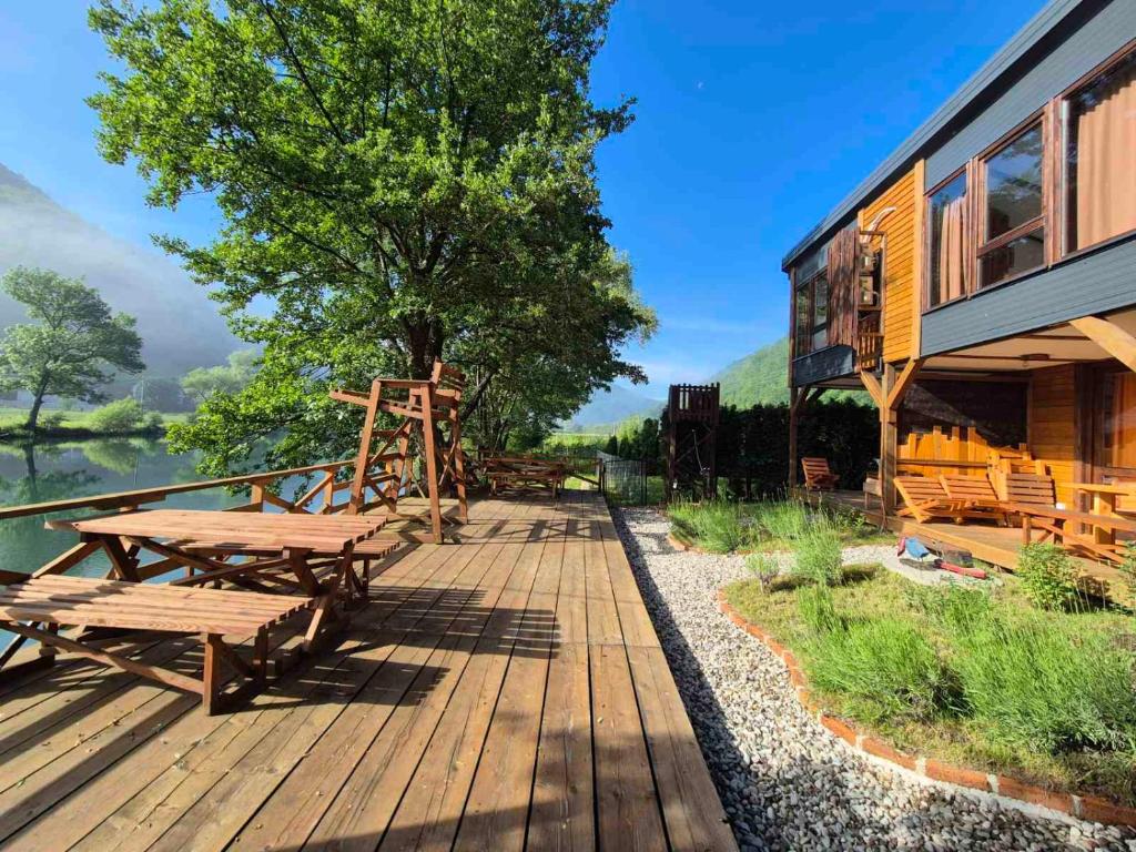 a wooden deck with picnic tables next to a building at Roots&River in Jezero