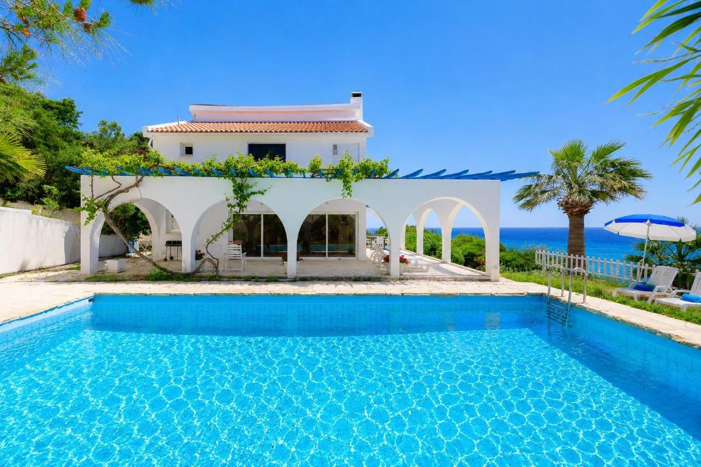a villa with a swimming pool in front of a house at Panorama Villa in Pomos