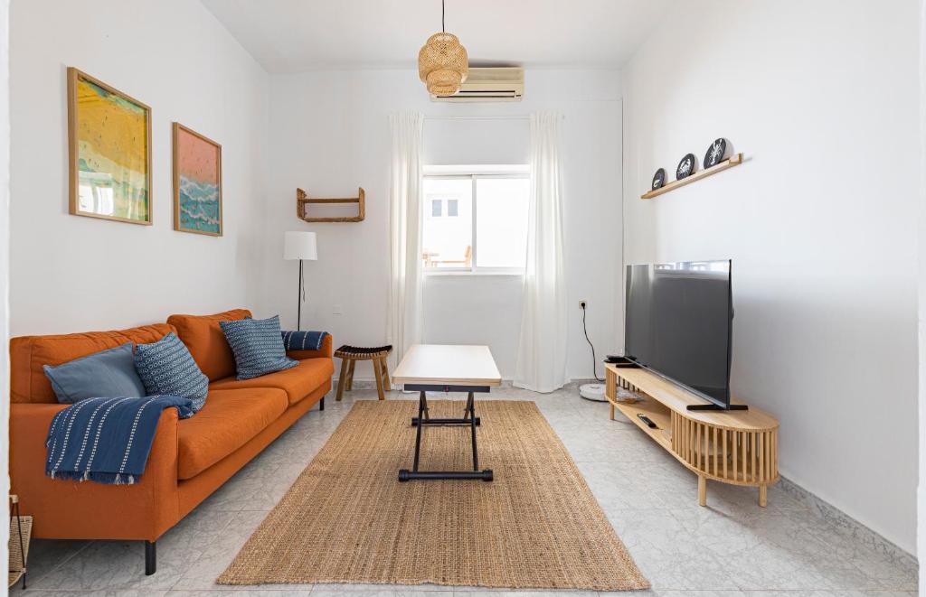 a living room with an orange couch and a flat screen tv at Casa Marina - Desayuno y parking incluidos in Portman