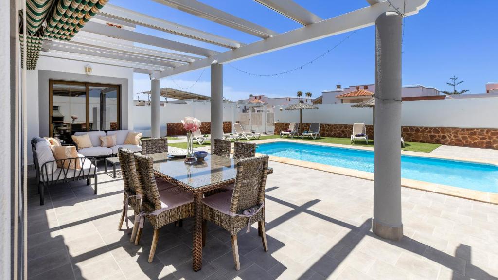 a patio with a table and chairs next to a pool at Villa with private pool, near beach and golf Caleta de Fuste- Villa Charlotte in Costa de Antigua