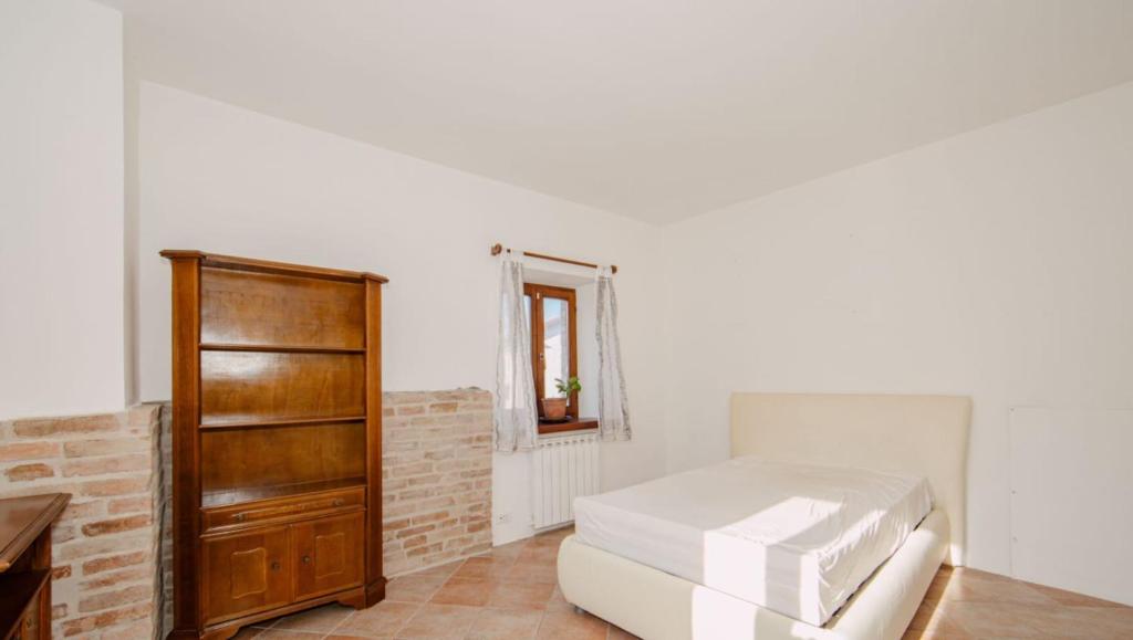a white room with a bed and a dresser at ERmETE in Tortona