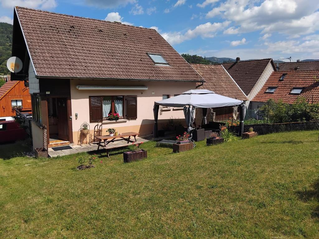 a house with a table and a umbrella in a yard at "Parenthèse Alsacienne" in Luttenbach-près-Munster