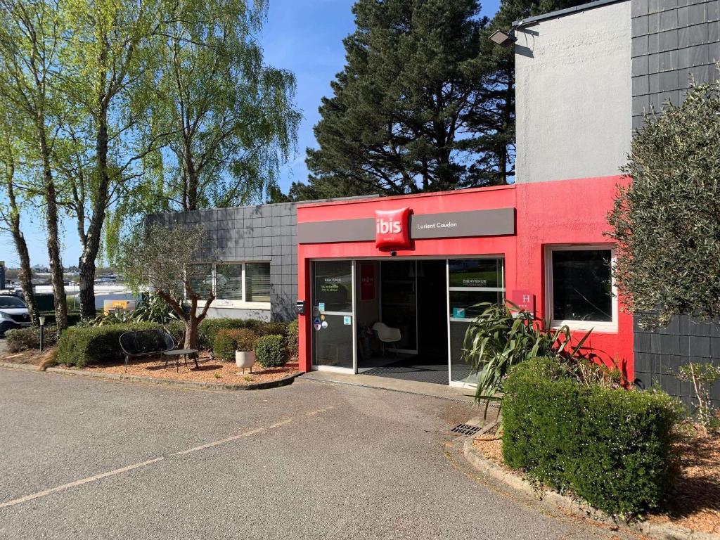 a red building with the entrance to a parking lot at ibis Lorient Centre Hôtelier in Caudan