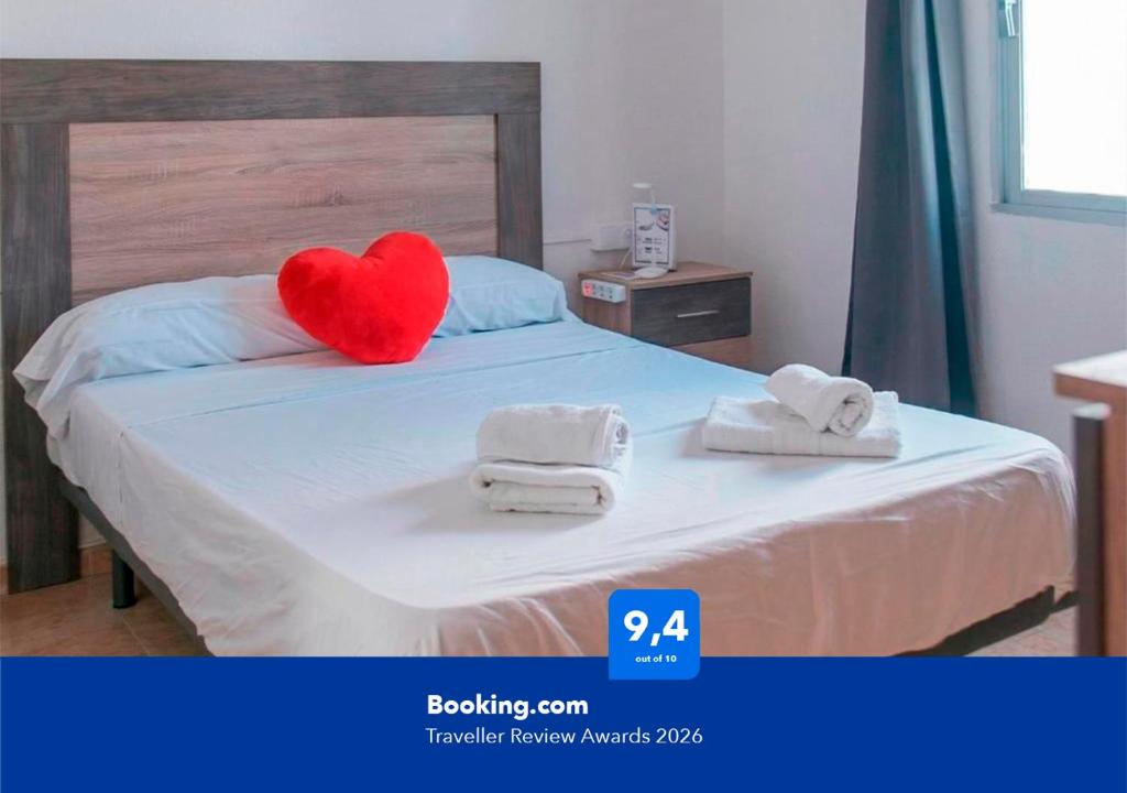 a red heart pillow sitting on a bed with towels at Apartalux Paraíso Azul in Barbate