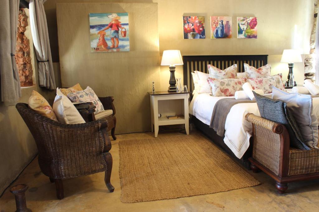 a bedroom with a bed and two chairs at Flitwick Ranch in Swartberg
