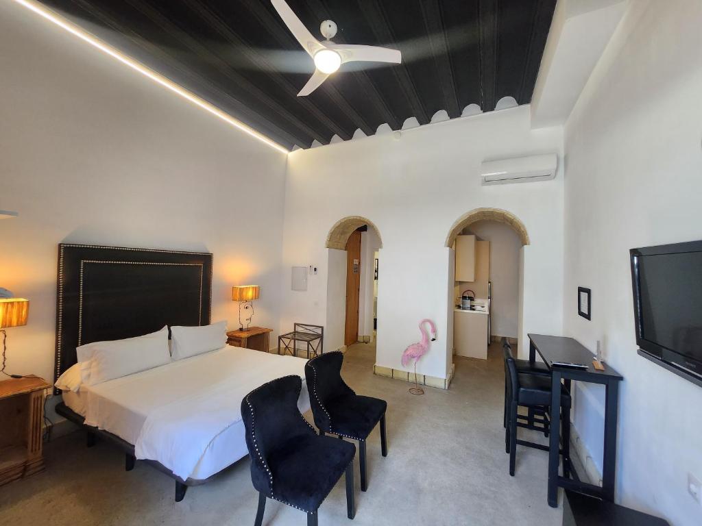 a bedroom with a bed and chairs and a flat screen tv at CAMASanlúcar in Sanlúcar de Barrameda