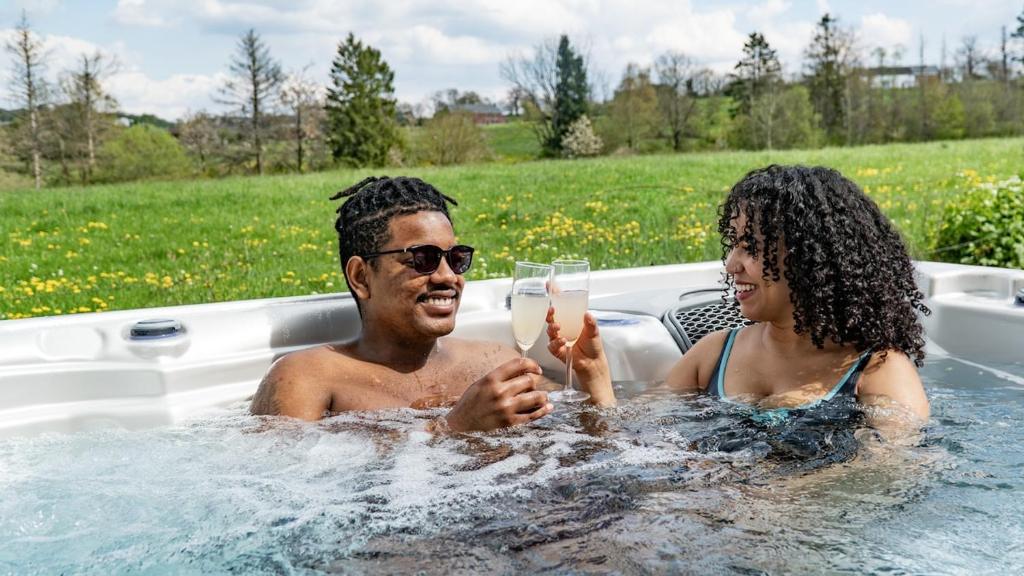 a man and a woman in a bath tub with a glass of champagne at Bosquet Secret in Froid-Chapelle