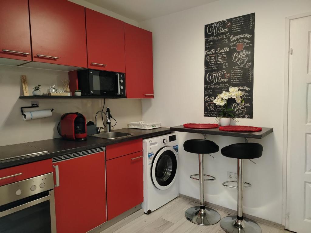 a kitchen with red cabinets and a washer and dryer at Csillag Vendégház in Debrecen