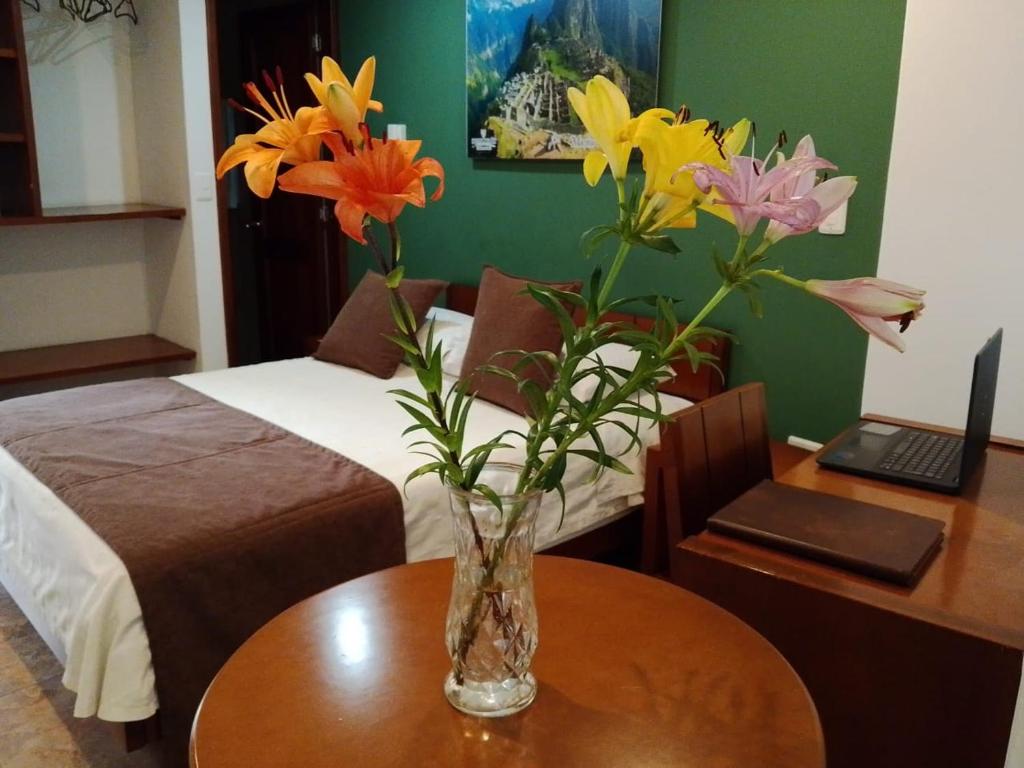 a vase of flowers on a table in a bedroom at Hotel Milán in Duitama