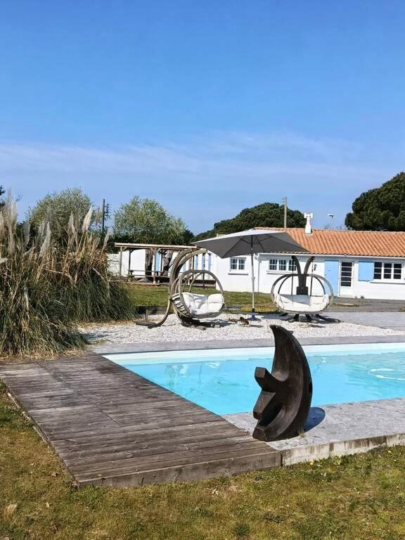 a swimming pool with a dolphin statue next to a house at L'Olivier des Dunes in Saint-Georges-dʼOléron