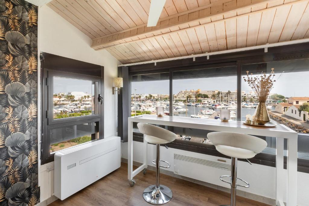 a bar with two stools in a room with windows at Studio naturiste venus panoramic view in Cap d'Agde