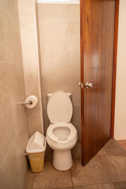 a bathroom with a toilet and a trash can at Happy Beach - Playa Feliz in Ixtapa-Zihuatanejo International