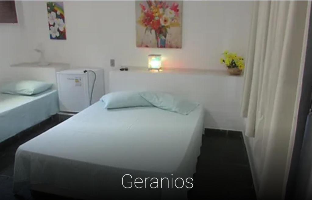 a bedroom with a white bed and a white wall at Pousada Tia Lucia in Saquarema