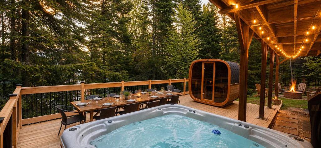 a jacuzzi tub on a deck with a table at Eko Eau Bonheur in Saint Adolphe D'Howard