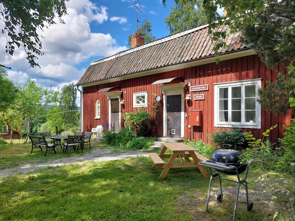 a red house with a picnic table and a grill at Cottage Lake view Dalarna - Tolvsbo in Söderbärke