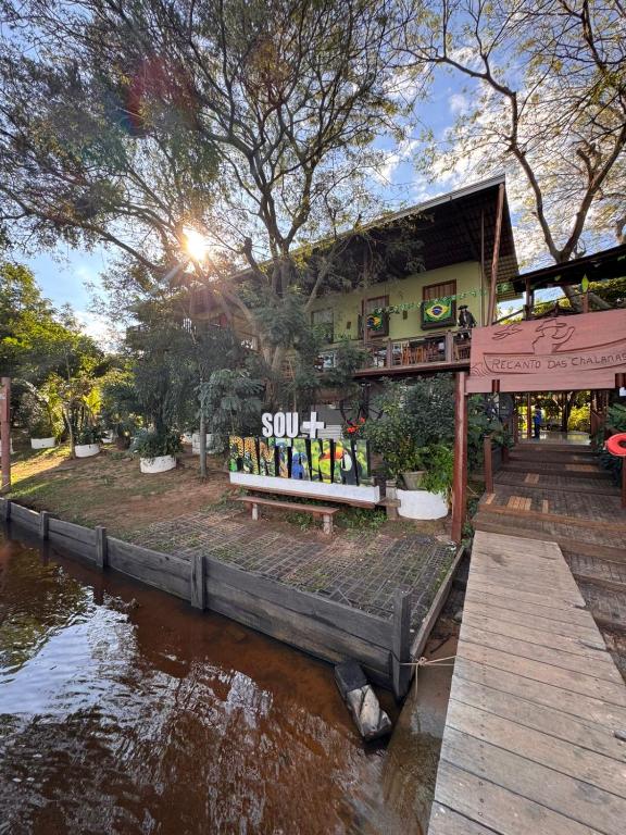 a building with a bench next to a body of water at Pousada Recanto das Chalanas in Corumbá