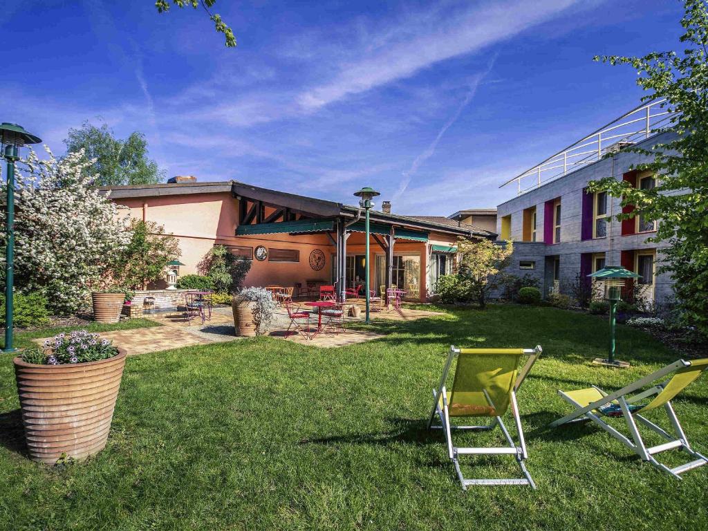a yard with two lawn chairs and a building at Mercure Bourg En Bresse in Bourg-en-Bresse