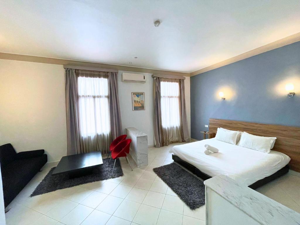 a bedroom with a large bed and a red chair at Hôtel Olympic in Fez