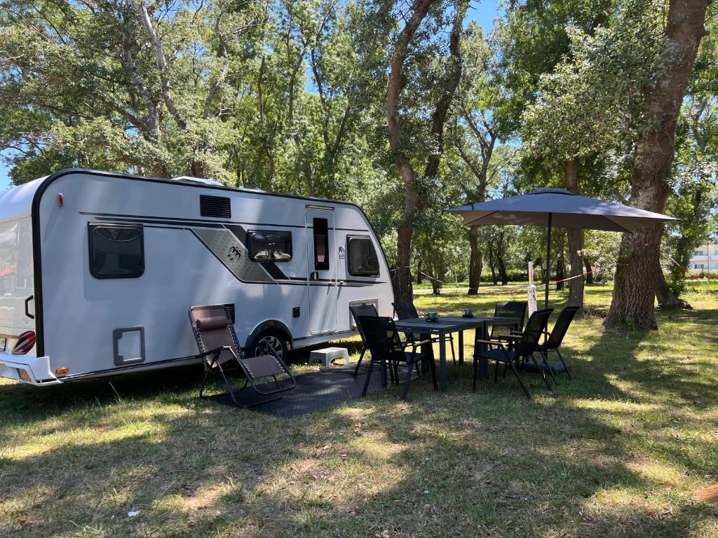 an rv parked next to a table with an umbrella at Neptun Beach Caravans in Ulcinj