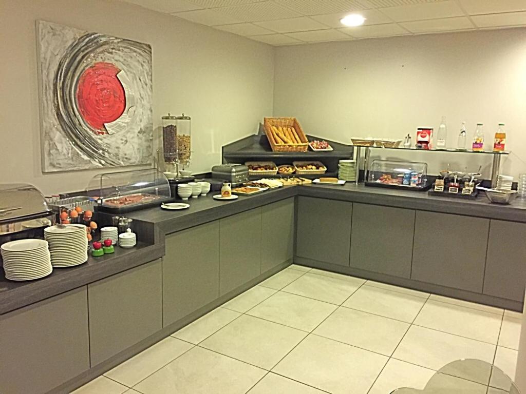 a restaurant kitchen with a counter with food at Le Domaine des Oliviers in Pierrelatte