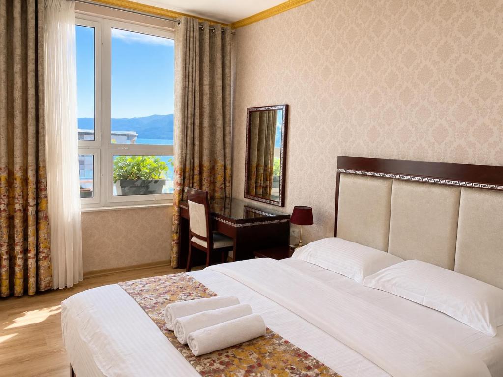 a bedroom with a bed and a desk and a window at British Hotel Pogradec in Pogradec