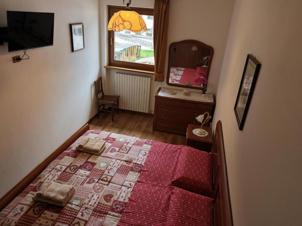 a bedroom with a bed and a dresser and a window at Winter and Summer Cortina in Cortina dʼAmpezzo