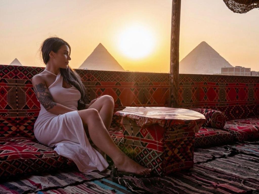 a woman sitting on a couch in front of pyramids at Explore Pyramids View in Cairo