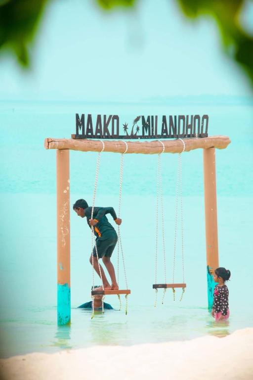 a man on a swing in the water at the beach at Maako Retreats in Milandu