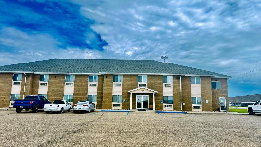 a large brick building with cars parked in a parking lot at Four Seasons Inn in Bottineau